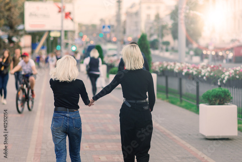 Two young females walking smiling embracing and kissing outdoor in the city