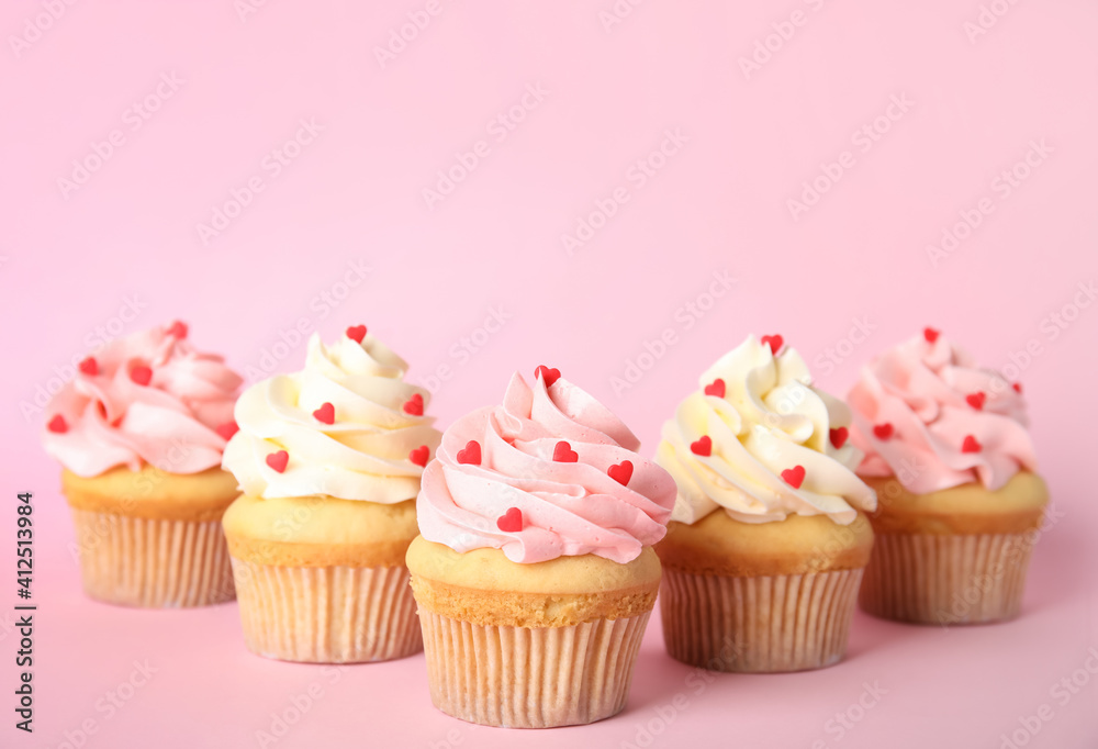 Tasty cupcakes with heart shaped sprinkles on pink background. Valentine's Day celebration