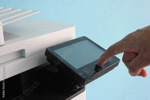 Closeup hand press button to using the photocopier or xerox machine is office work tool printer equipment in copy room for scanning document and print a paper.