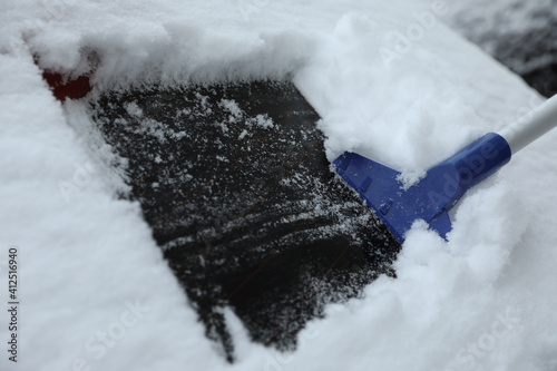 Cleaning car from snow outdoors on winter day, closeup. Frosty weather