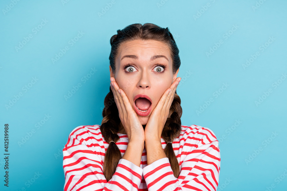 Photo of young girl amazed shocked surprised news fake novelty hands touch cheeks isolated over blue color background Photo of young girl amazed shocked surprised news fake novelty hands touch cheeks isolated over blue color background