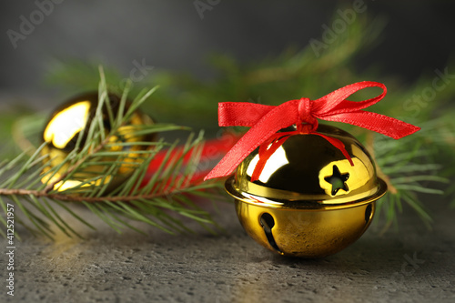Canvas Print Golden sleigh bells and fir branches on grey background, closeup