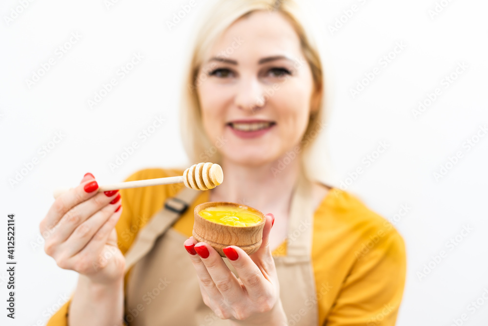 Happy young woman holding wooden bowl of honey, copy space Happy young woman holding wooden bowl of honey, copy space