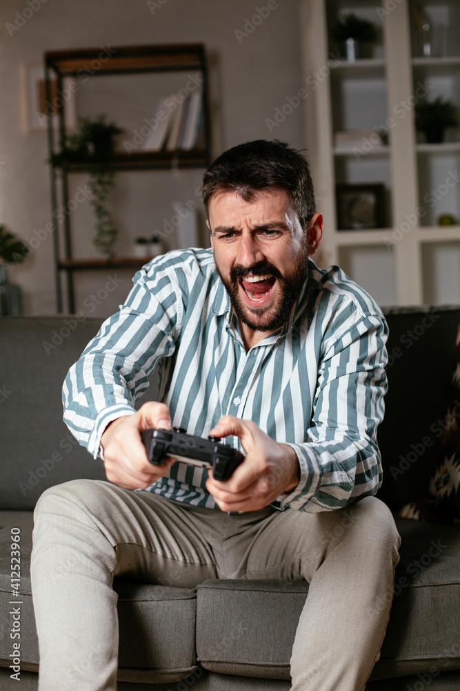Young attractive man playing video games in the living room. Handsome man having fun at home.. Young attractive man playing video games in the living room. Handsome man having fun at home..