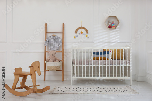 Fototapeta Naklejka Na Ścianę i Meble -  Cute baby room interior with comfortable crib and wooden rocking horse