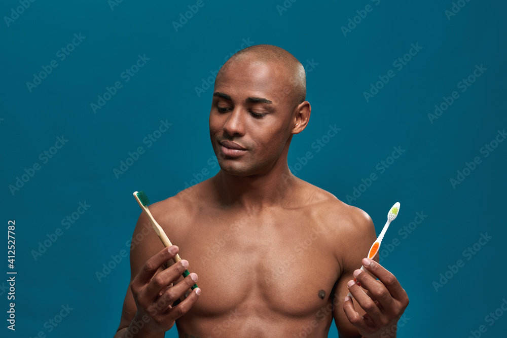Fototapeta premium Afro-American man watching positively the eco friendly toothbrush