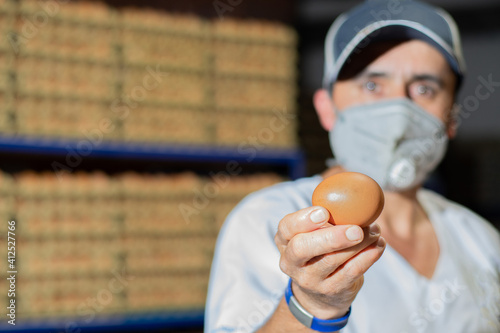 Fresh chicken egg in hand from organic farm. Industrial chicken egg farm. egg. Farmer with fresh egg in hand and mask.