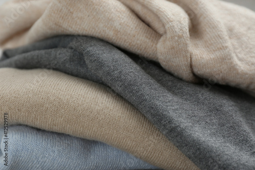 Stack of cashmere clothes as background, closeup photo