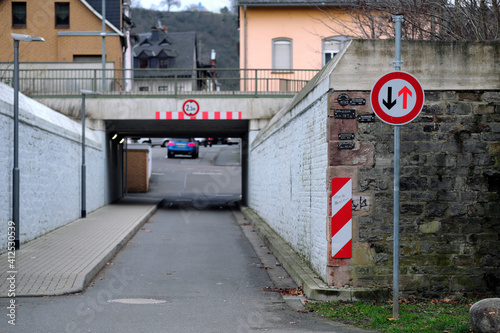 Verkehrsschild mit Verkehrszeichen Vorrang des Gegenverkehrs vor Bahnunterführung und Hochwassermarken des Rheins bei Lahnstein - Stockfoto