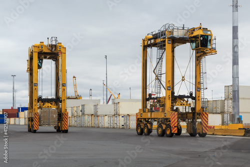 Two straddle carriers, giant vehicles used to move shipping containers, in a cargo terminal photo
