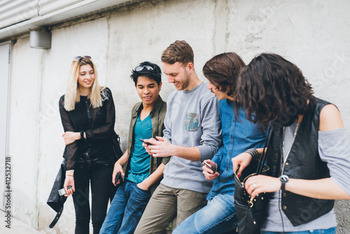 Group of multiethnic friends millennials using smartphone