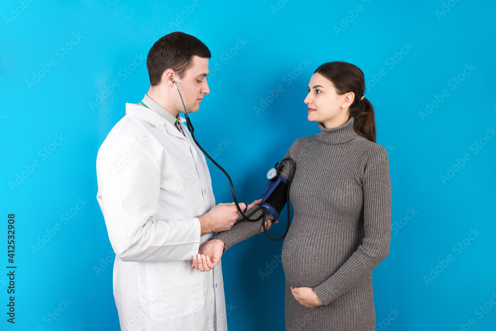 doctor measures the pressure of a pregnant woman on colourful background doctor measures the pressure of a pregnant woman on colourful background