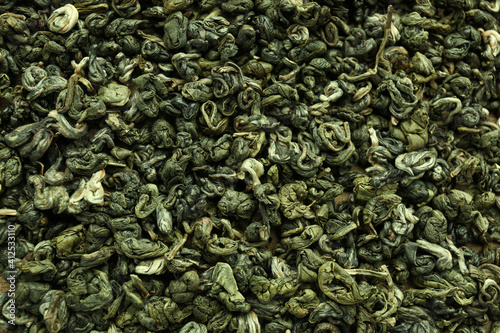 Dry green tea leaves as background, top view