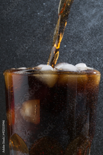 Soda drinks pouring into glass macro in studio