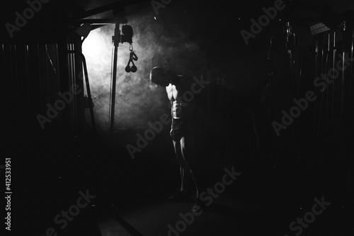  Awesome bodybuilder silhouette. Handsome power athletic man bodybuilder. Fitness muscular body on dark colour smoke background. Perfect male. tattoo, posing.