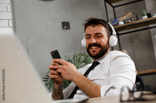 Attractive businessman in office. Young businessman with headphones singing at work
