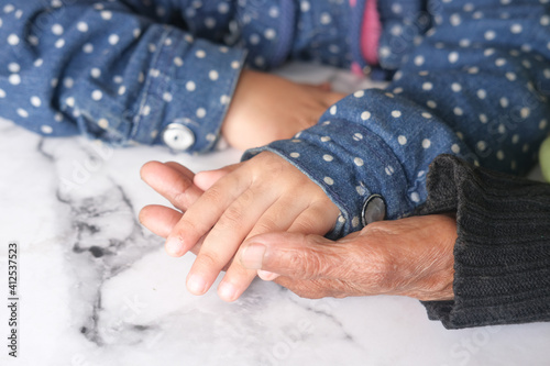 close up of child hand holding senior women's hand 