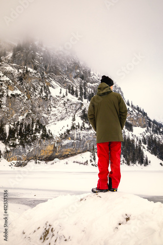Wallpaper Mural Man looking to the horizon in front of a frozen lake in a snowy mountain landscape Torontodigital.ca