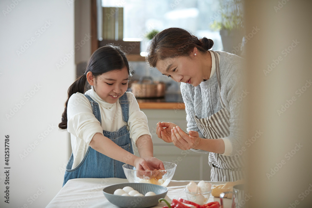Happy adorable little child girl in apron enjoying cooking homemade pastry together with grandmother at home. Happy adorable little child girl in apron enjoying cooking homemade pastry together with grandmother at home.