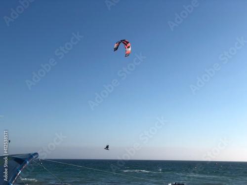 Persona en la playa practicando kitesurf con la cometa en el cielo azul