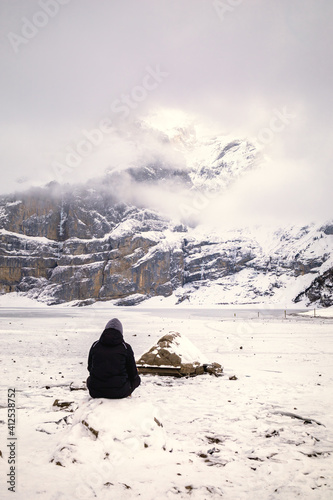 Wallpaper Mural Woman sitting in front of a frozen lake in snowy mountain landscape Torontodigital.ca