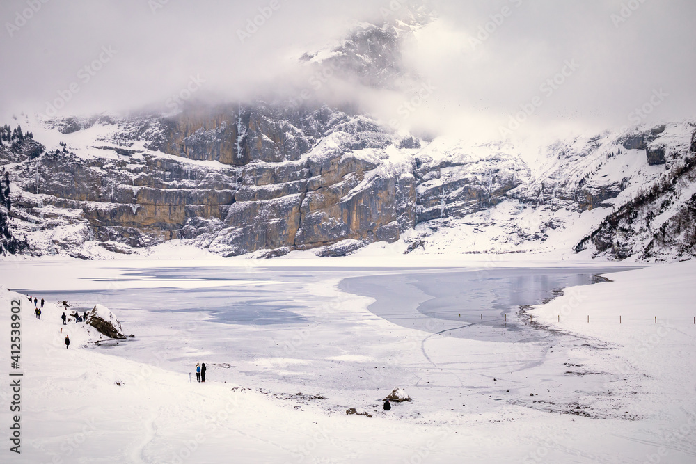 People spending day by frozen lake in snowy mountain landscape
