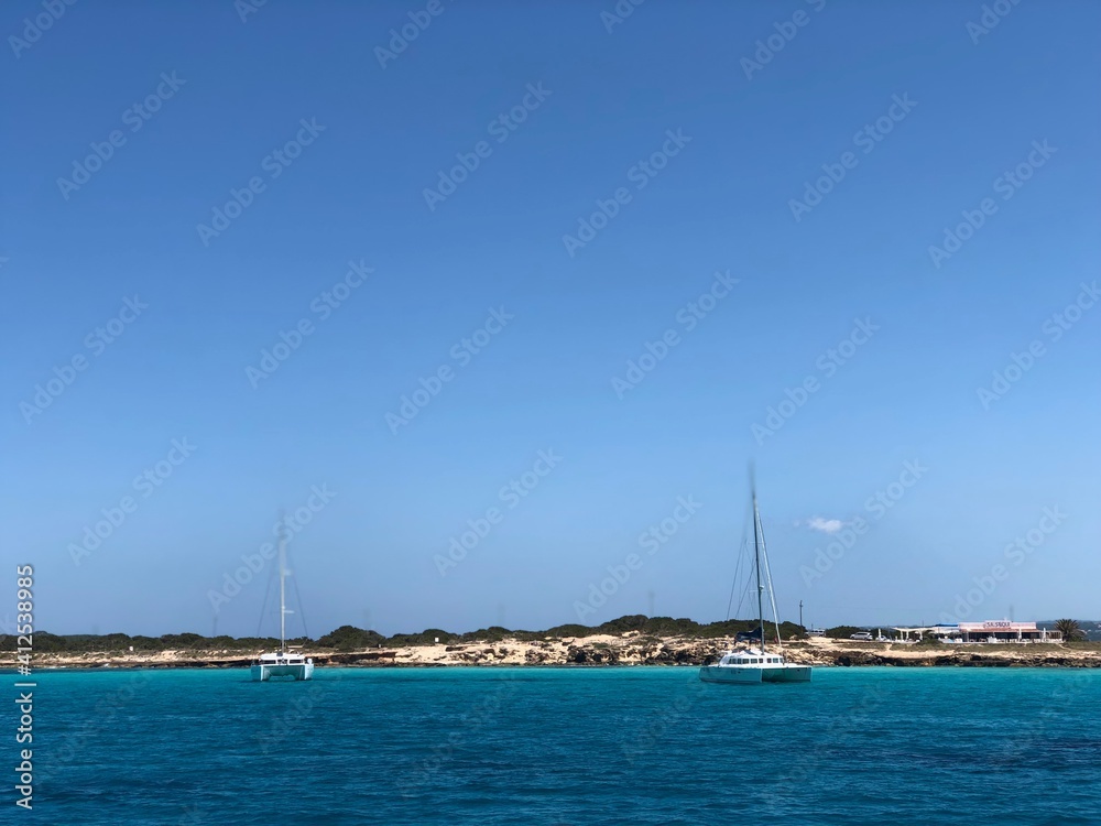 barcos y veleros fondeados en las aguas azul turquesa de formentera