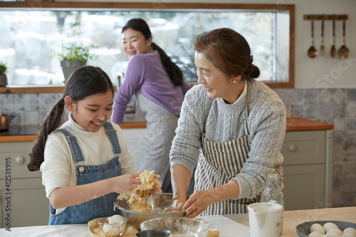 Happy adorable little child girl in apron enjoying cooking homemade pastry together with family at home.