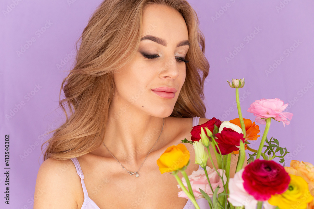 A girl in a silk dress holds a bouquet of flowers. Beautiful girl for Valentine's Day with a bouquet in her hands. Beautiful girl on March 8. Portrait of a girl on a purple background with flowers.