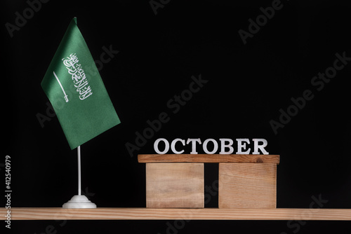 Wooden calendar of October with Saudi Arabia flag on black background. Dates of Saudi Arabia in October