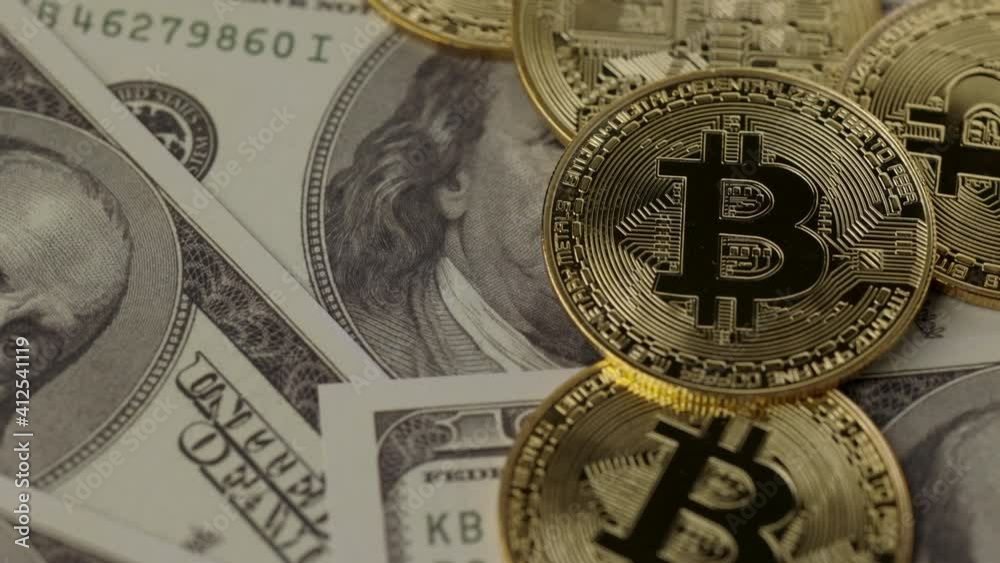 Close-up golden Bitcoins on a background of dollars.Close-up bitcoins. Exchange bitcoin for cash to a dollar. Rotates slowly. Crypto currency. Close-up golden Bitcoins on a background of dollars.Close-up bitcoins. Exchange bitcoin for cash to a dollar. Rotates slowly. Crypto currency.