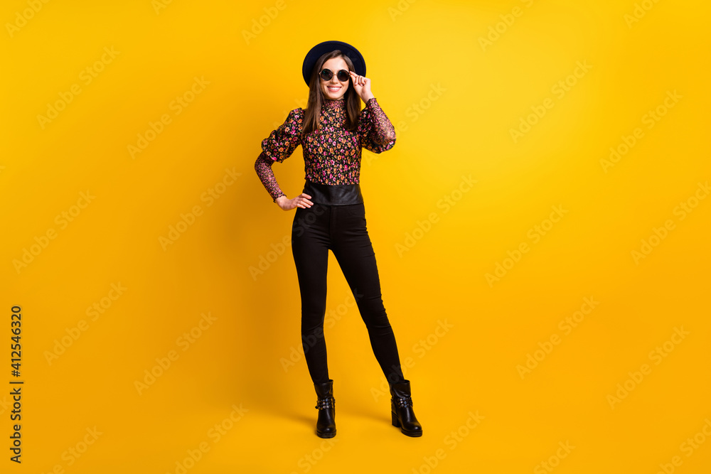 Full length body size photo of girl wearing printed fashion clothes sunglass black headwear smiling isolated bright yellow color background Full length body size photo of girl wearing printed fashion clothes sunglass black headwear smiling isolated bright yellow color background
