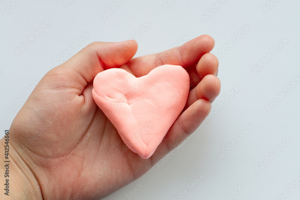 Hands holding pink heart made of plasticine Hands holding pink heart made of plasticine
