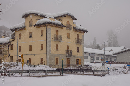 Typical italian villa with closed window blinds or wooden covers in the citiy of Vodo di Cadore during heavy snow. © Anze