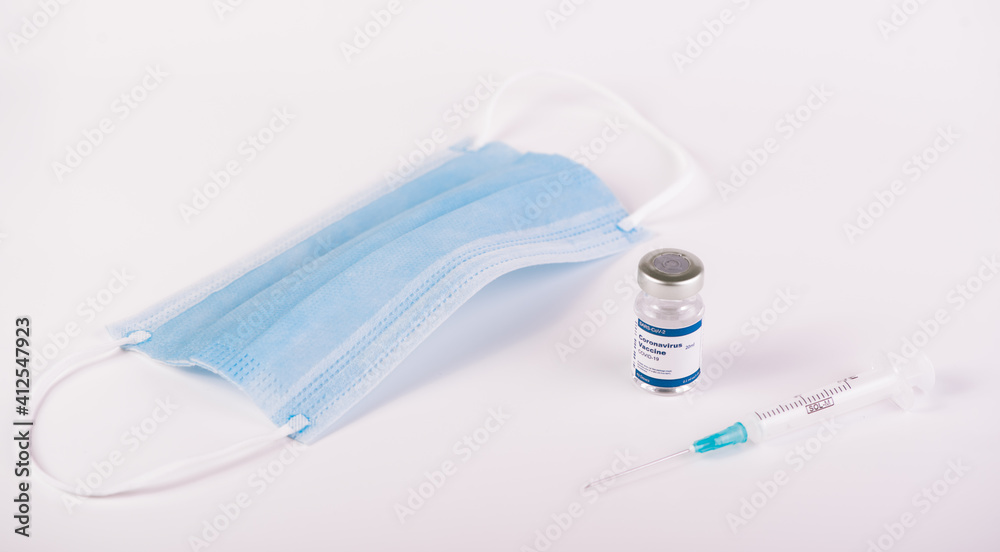 One Covid-19 vaccine vial, syringe and blue mask with white One Covid-19 vaccine vial, syringe and blue mask with white