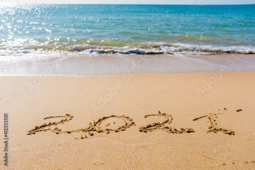 2021 year sign hand written sandy beach sunny outdoors background. © gorosi