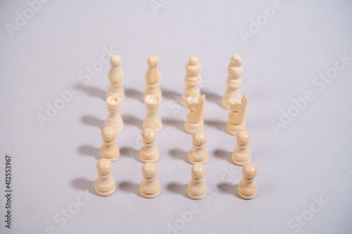 white chess pieces standing against gray background in the shape of a square