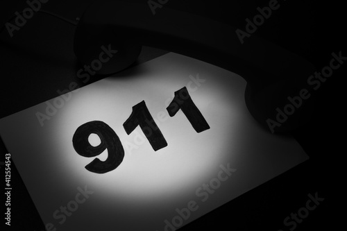 Call 911 and emergency call concept, text 911 on paper and phone isolated on black. photo