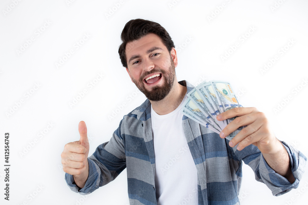 Portrait of smart, rich, rich, friendly, cheerful, excited entrepreneur, with a shining smile, showing many banknotes in his hand with his index finger isolated on white background. Portrait of smart, rich, rich, friendly, cheerful, excited entrepreneur, with a shining smile, showing many banknotes in his hand with his index finger isolated on white background.