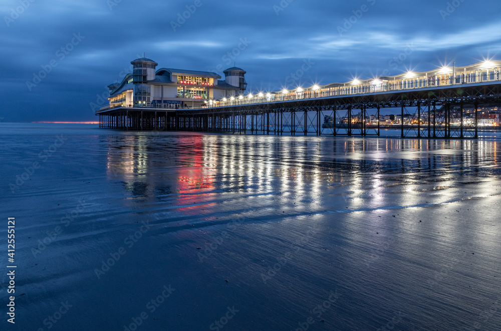 Long Exposure Image Of Weston-super-Mare Pier With Reflected Lights On The Wet Sand