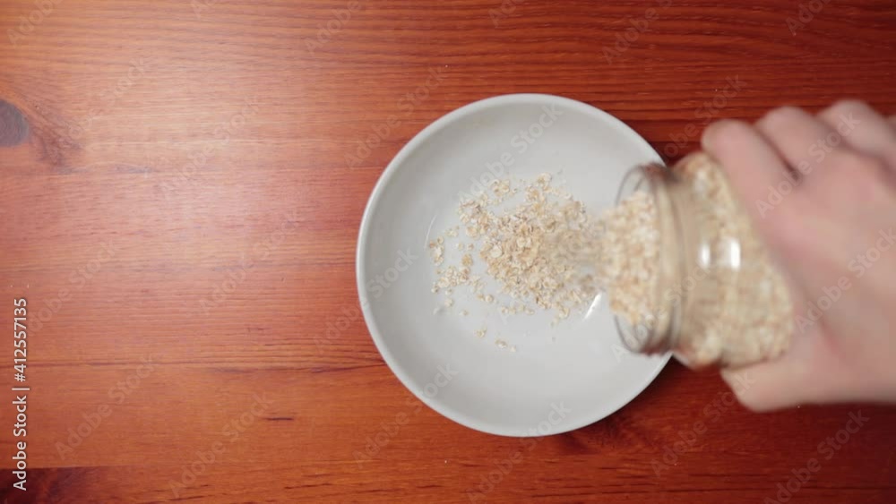 Overhead shot of a woman pouring oat flakes into a bowl Overhead shot of a woman pouring oat flakes into a bowl