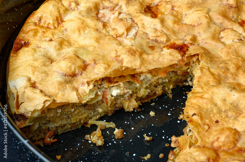 Delicious Greek Pontic-style homemade meat pie in black roasting pan Delicious Greek Pontic-style homemade meat pie in black roasting pan