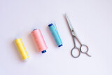 colorful different threads with scissors amd needle on white background with free copy space, equipment for sew, materials for sewing