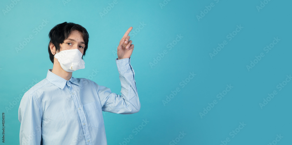 Pointing. Man in protective face mask isolated on blue studio background. New rules of COVID spreading prevention. Copyspace for ad. Pandemic, healthcare and medicine, coronavirus concept. Flyer Pointing. Man in protective face mask isolated on blue studio background. New rules of COVID spreading prevention. Copyspace for ad. Pandemic, healthcare and medicine, coronavirus concept. Flyer