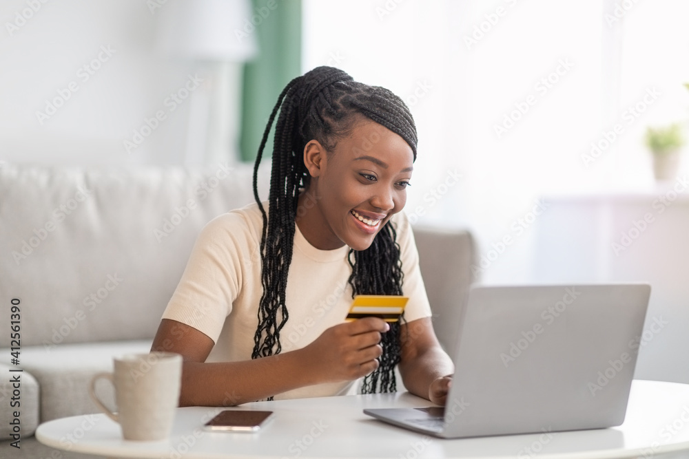 Positive black woman holding credit card, using laptop Positive black woman holding credit card, using laptop