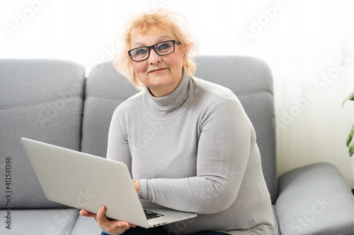 Smiling elderly senior woman with laptop at home