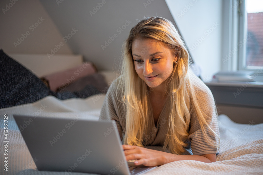 Girl lying on her bed studies remotely through her laptop.She is in quarantine and stays at home so as not to spread the coronavirus Girl lying on her bed studies remotely through her laptop.She is in quarantine and stays at home so as not to spread the coronavirus