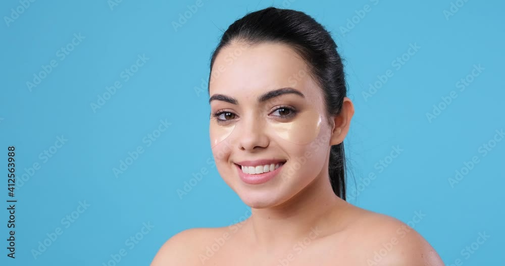 Beautiful woman with flawless clean skin and under eye patches over blue background Beautiful woman with flawless clean skin and under eye patches over blue background