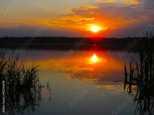 Beautiful summer sunset over the lake.  Reflection of sunset in the water.  Sunny summer evening.