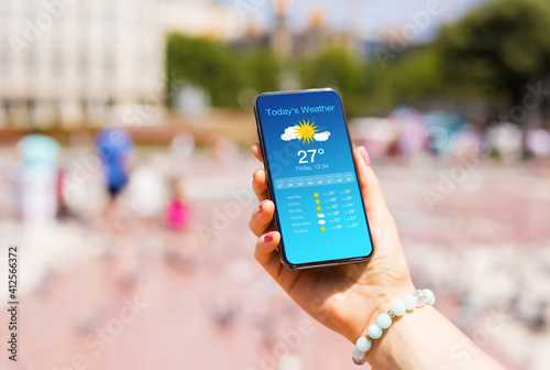 Quadro su tela Woman outside in city checking weather forecast on her mobile phone